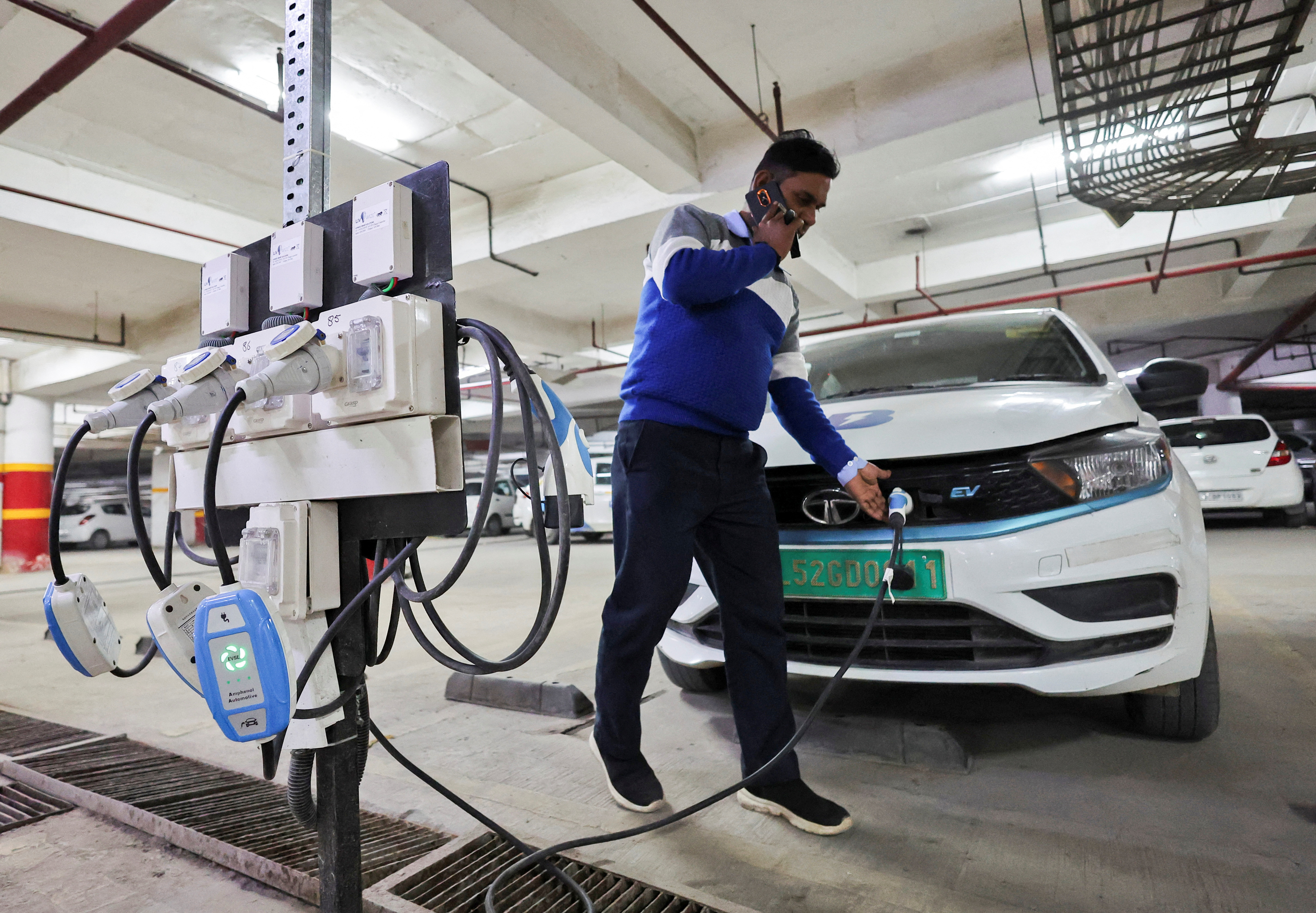 A man charges an electric vehicle (EV) at the charging hub of Indian ride-hailing BluSmart Electric Mobility in Gurugram, India, December 9, 2022. REUTERS/Anushree Fadnavis